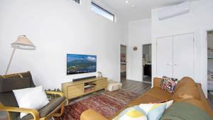 a living room with a couch and a tv at Summer Vibes Cabin Wifi in Ettalong Beach