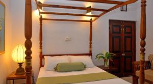 a bedroom with a canopy bed with a green pillow on it at Villa Capers in Colombo