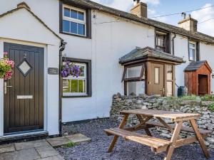 a wooden picnic table in front of a white cottage at Kidsty Cottage in Penrith