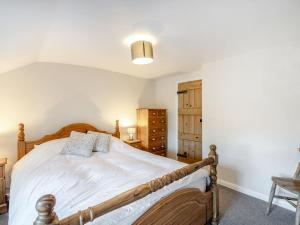 a bedroom with a wooden bed and a chair at Kidsty Cottage in Penrith