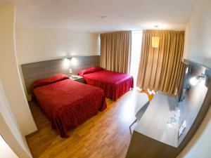 Habitación de hotel con 2 camas con colchas rojas en Hotel Del Angel Reforma, en Ciudad de México