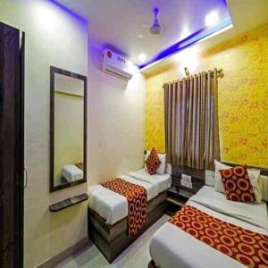 a hotel room with two beds and a mirror at Hotel New Sarah Inn, Andheri West in Mumbai