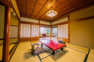 a room with a table and chairs and windows at Yunoshimakan in Gero