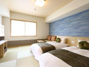 two beds in a room with a window at Onyado Nono Sendai Natural Hot Spring in Sendai