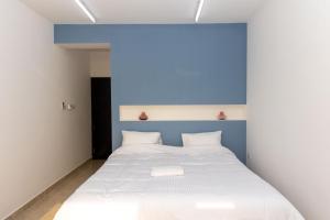 a bedroom with a white bed with a blue headboard at استراحة نادي اورجان Orjan Guest House in Camp