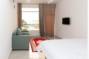 a bedroom with a bed and a couch and a window at استراحة نادي اورجان Orjan Guest House in Camp
