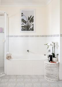 a white bathroom with a tub and a plant at Casa Keys Shoal Bay in Shoal Bay