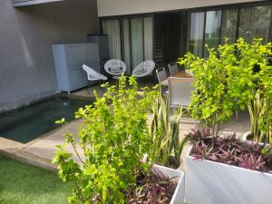 a patio with chairs and a pool with plants at Latitude - with private plunge pool in Rivière Noire