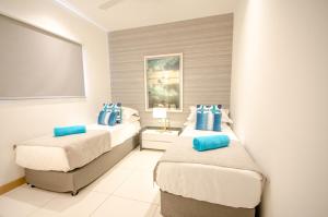 a bedroom with two beds with blue pillows at Latitude - with private plunge pool in Rivière Noire