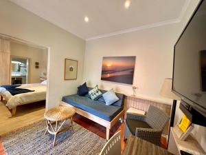 Sala de estar con sofá, cama y TV en The Secret Garden Guesthouse, en Swakopmund