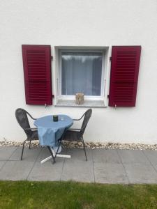 Ein Tisch und zwei Stühle vor einem Fenster in der Unterkunft Happy Connection in Villarvolard