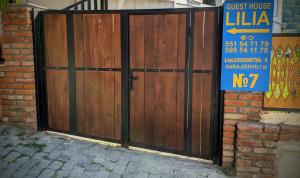 un cancello in legno con un cartello di fronte a una casa di Lilia guesthouse a Sighnaghi