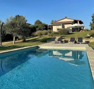 a swimming pool with chairs and a house at Nonno Gino suite in Monte San Savino