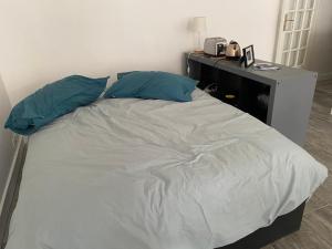uma cama com duas almofadas azuis e uma secretária em Studio Plein Centre em Rambouillet
