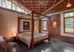 a bedroom with a canopy bed in a brick wall at Estate Stay - Riverside Coffee in Siddapur