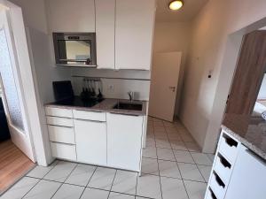 uma cozinha com armários brancos e um lavatório em Nordland Appartements - Wohnung Sylt em Wyk auf Föhr