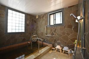 a bathroom with a shower with a stone wall at Private Beppu Tanoyu Onsen in Beppu