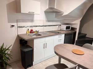 uma pequena cozinha com um lavatório e uma mesa em YellowHouse - Teleworking- Wifi - CosyHouseByJanna em Châtellerault