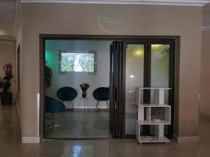 a hallway with two chairs and a glass door at Palm Valley Inn in Hartbeespoort
