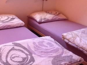 - 3 lits dans une chambre avec des draps violets dans l'établissement La Tourelle, à Tartegnin