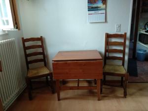 Duas cadeiras e uma mesa de madeira com uma secretária entre duas cadeiras. em La Tourelle em Tartegnin