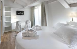 a white bedroom with a bed and two chairs at Rimini Suite Hotel in Rimini