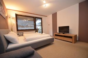 a bedroom with a bed and a tv and a couch at Studio 13 - by Four Seasons Apartments in Kaprun