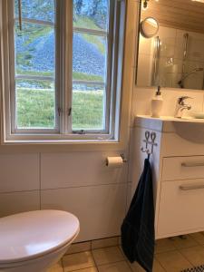 a bathroom with a toilet and a sink and a window at Unstad cabin with seaview in Unstad