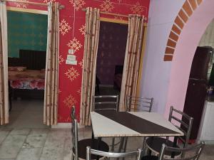 DooN Resort & Farmhouse stay في دهرادون: طاولة وكراسي في غرفة بجدار احمر