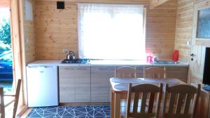 a kitchen with a refrigerator and a table and chairs at Domki Muszelka in Stegna