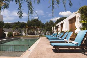 una fila di sedie a sdraio blu accanto alla piscina di Bruma Luxury Residence a Mouzákion
