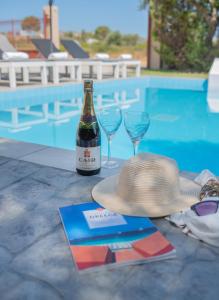 kapelusz i dwa kieliszki wina obok basenu w obiekcie Emma's Luxury Villa w mieście Pastida