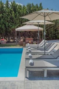 szereg leżaków z parasolami i basen w obiekcie Emma's Luxury Villa w mieście Pastida