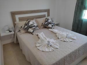 uma cama com lençóis brancos e almofadas em Els Pilanets em Sant Carles de la Ràpita