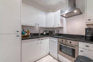a kitchen with white cabinets and a stove top oven at One Bedroom - Tower Bridge - London City by Prime London Stays M-10 in London