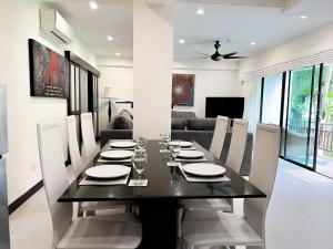 a dining room with a black table and white chairs at The Sands : 3 Bedrooms Naiharn Beachside Apartment in Nai Harn Beach