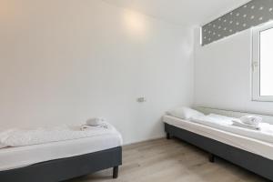 Duas camas num quarto com paredes brancas e uma janela em Smallengange 45 em Kortgene