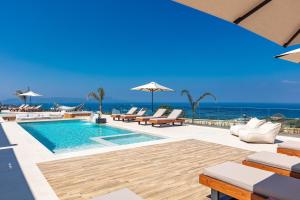 - une piscine avec des chaises et l'océan en arrière-plan dans l'établissement Mageia Exclusive Residence, à Vederoi