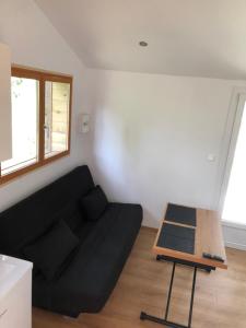 salon z czarną kanapą i stołem w obiekcie Tiny house détente nature la maison du pêcheur w mieście Pulligny