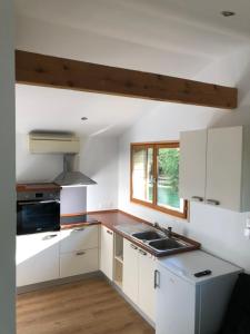 una cucina con mobili bianchi, un lavandino e una finestra di Tiny house détente nature la maison du pêcheur a Pulligny Altre 15 foto