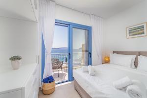 a white bedroom with a bed and a balcony at Greek Beach House Complex B4 in Nydri