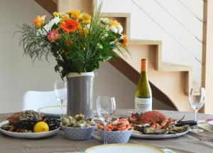 una mesa con platos de comida y una botella de vino en COTE CIEL - CANCALE - GITE STANDING - PROCHE CENTRE ET PORT, en Cancale