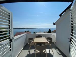 a small balcony with a wooden table and chairs on it at Emanuela 2 in Novalja