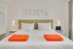 a bed with two orange pillows on top of it at LIVINGHOME SUITES in Parga +53 photos