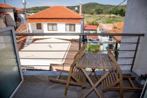 a wooden chair sitting on a balcony with a house at elenamou rooms in Ammouliani +16 photos