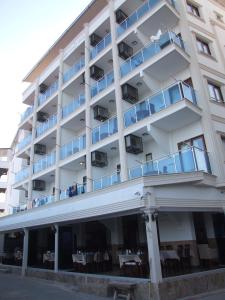 un edificio de apartamentos con balcón, mesas y sillas en Nisan Hill Hotel, en Kızkalesi