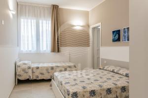 トッレ・ラピッロにあるVilla Sabbia Biancaのベッド2台と窓が備わる小さな客室です。