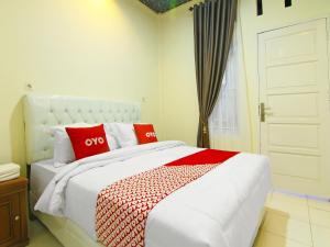 um quarto com uma cama grande e almofadas vermelhas em OYO 90978 Khalifi Guesthouse Syariah em Padang