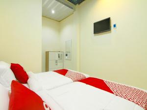 1 dormitorio con 2 camas y almohadas rojas y blancas en OYO 90978 Khalifi Guesthouse Syariah en Padang