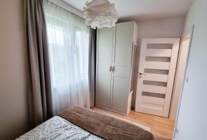 sypialnia z łóżkiem, szafą i żyrandolem w obiekcie Apartament Młody Gdańsk - bezpłatny parking, mocne WiFi, dobre połączenie z lotniskiem w Gdańsku